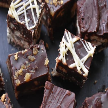 Chocolate Tiffin cut into squares on a black board.
